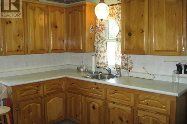 Kitchen with light wood cabinets, white countertops, and a double sink. - 103 Highway 8, Milton