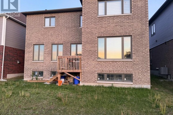 Rear exterior of a brick house with a wooden deck and basement windows. - 103 Nottingham Road, Barrie