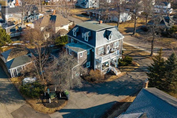 Aerial view of a dark grey multi-family home with a metal roof and a detached garage. - 103 Olde Brighton Lane, Charlottetown