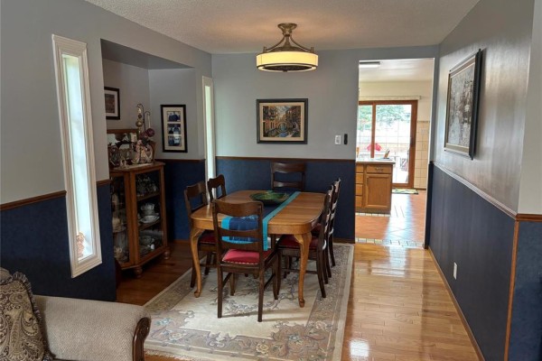 View of the dining room and a doorway leading to the kitchen with warm wooden cabinetry. - 103 Pear Tree Bay, Winnipeg