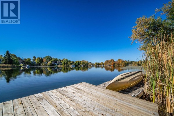 Wooden dock on a wide calm lake with cottages and trees in the distance. - 103 Rocklind Close Lane, Front Of Leeds & Seeleys Bay