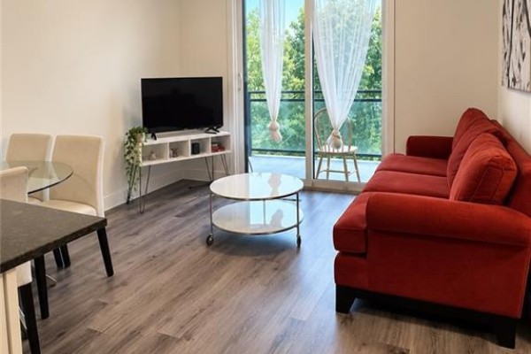 Living space with red sofa, coffee table, dining set, and balcony view. - 103 Roger Street Unit# 308, Waterloo