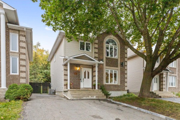 Side exterior view of a two-story brick and siding townhouse with a large tree in the yard. - 103 Rue Louis-colin, Gatineau