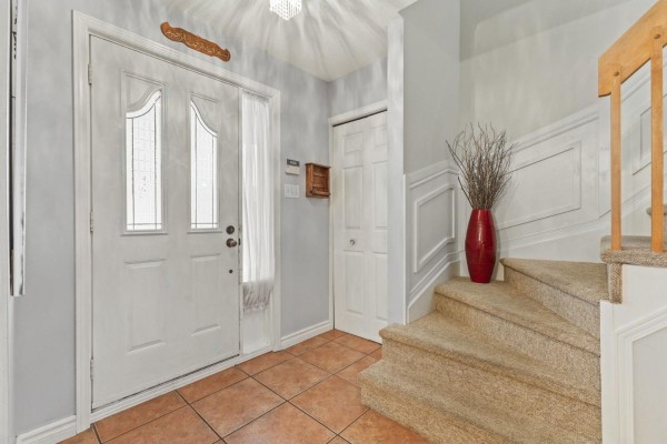 Interior entryway with a white double door, tile flooring, and carpeted stairs with wooden banister. - 103 Rue Louis-colin, Gatineau