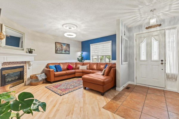 Living room with a large brown sectional sofa, fireplace, wood floors, and view of the entryway. - 103 Rue Louis-colin, Gatineau