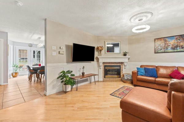 Living room with a large brown sectional sofa, fireplace, wood floors, and view of the dining area. - 103 Rue Louis-colin, Gatineau