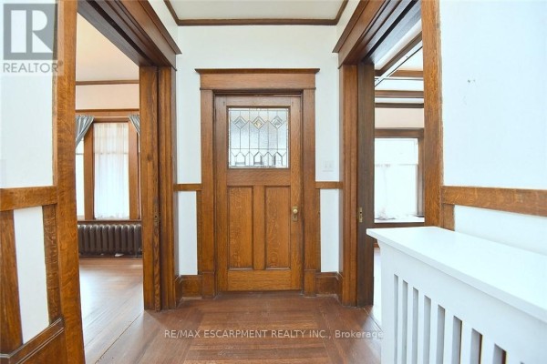 Interior hallway with oak wood trim, a stained glass door, and wood floors. - 103 Sherman Avenue S, Hamilton