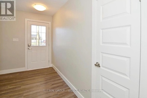 Interior hallway with a front door and two interior doors, light wood laminate flooring. - 103 Westbury Avenue, London South