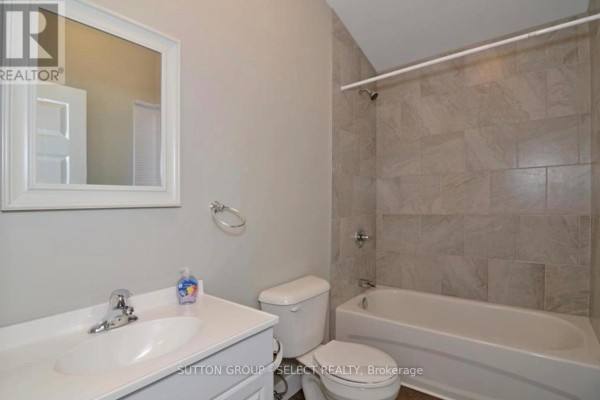 A bathroom with a white vanity, toilet, and bathtub with tiled walls. - 103 Westbury Avenue, London South