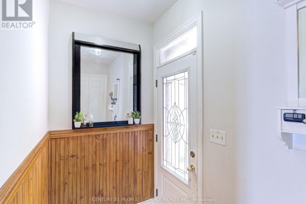 Interior entryway with a white door, large mirror, and wood-paneled accent wall. - 103 Whitchurch Mews, Mississauga