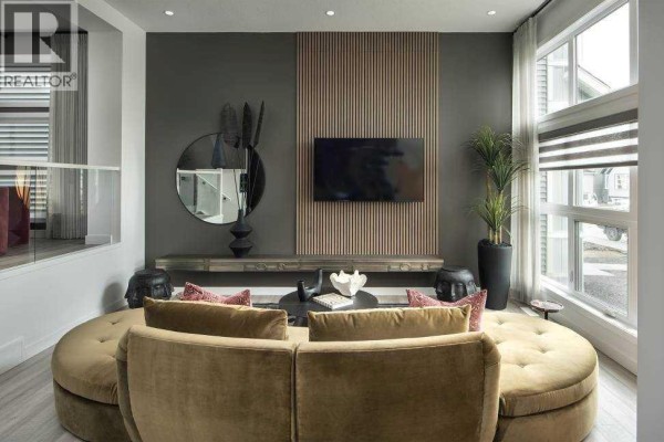 Living room with a large curved sofa, wall-mounted TV, and wood slat accent wall. - 103 Wolf Hollow Rise Se, Calgary