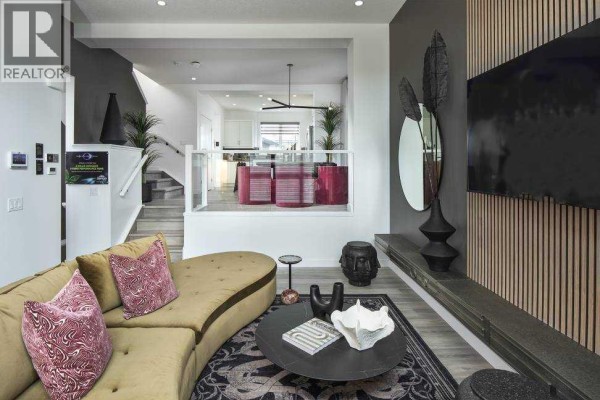 Living room with curved sofa, coffee table, and view into the dining area and kitchen. - 103 Wolf Hollow Rise Se, Calgary
