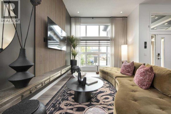 Living room with a curved sofa, patterned rug, and view of a large window. - 103 Wolf Hollow Rise Se, Calgary