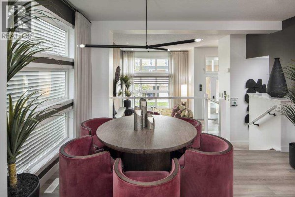 Round dining table with red chairs in a bright room with large windows and drapes. - 103 Wolf Hollow Rise Se, Calgary