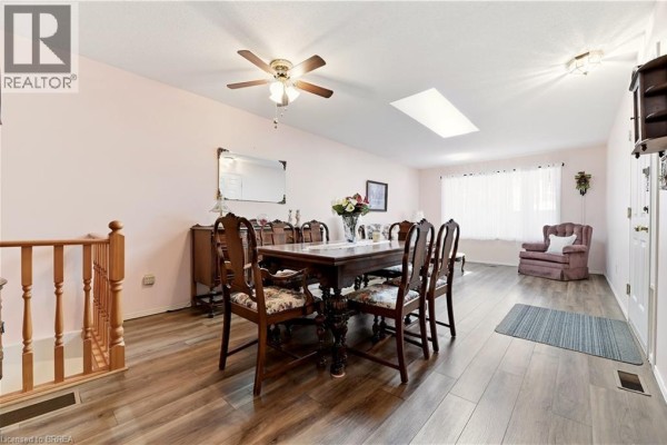 Dining room with dark wood table and chairs, buffet, and railing to lower level. - 1030 Colborne Street E Unit# 19, Brantford