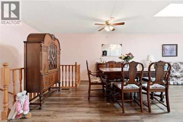 Dining area with wood hutch, dining table, floral chairs, and staircase railing. - 1030 Colborne Street E Unit# 19, Brantford