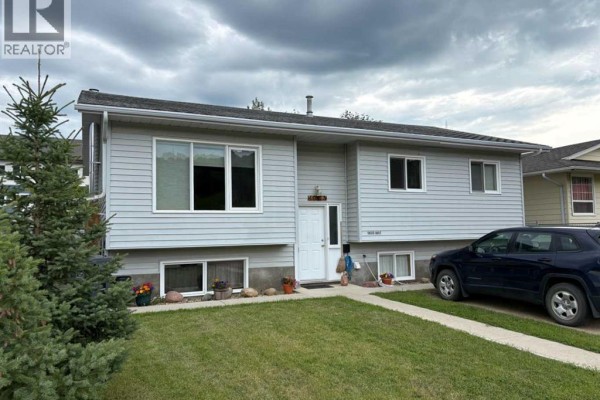 Kitchen with light wood cabinets, dark countertops, white dishwasher, and a window. - 10313 89 Street, Peace River