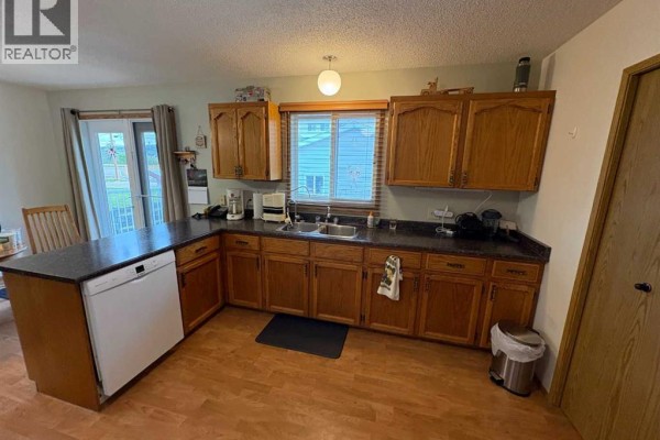 Kitchen with white appliances including a stove, microwave, and a refrigerator. - 10313 89 Street, Peace River