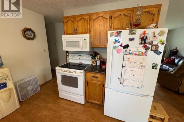 Wide view of the kitchen showing cabinets, appliances, a sink, and double doors. - 10313 89 Street, Peace River