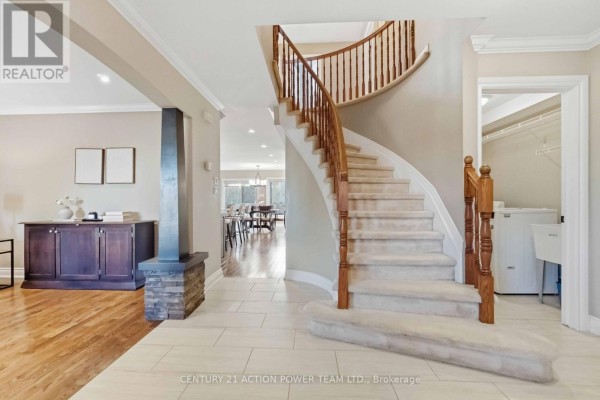 Curved staircase with wood banister and beige carpet treads. - 1032 Sheenboro Crescent, Ottawa