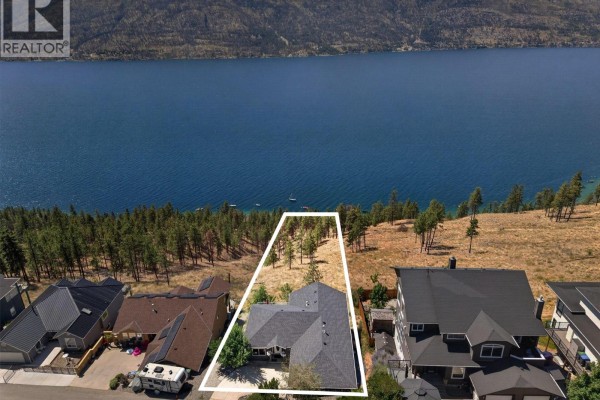 Aerial view of a home with a white outline on a hillside property facing a large blue lake. - 10326 Nighthawk Road, Lake Country