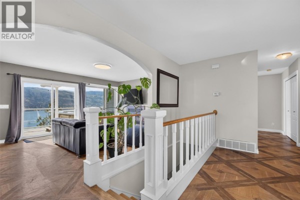 Interior view showing a staircase with white spindles and wood floors leading to a living area. - 10326 Nighthawk Road, Lake Country