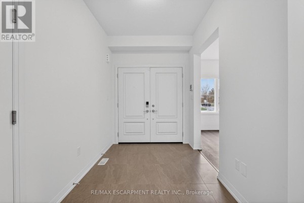 Spacious foyer with double white doors, white walls, and dark brown tile flooring. - 1034 Kraft Road N, Fort Erie