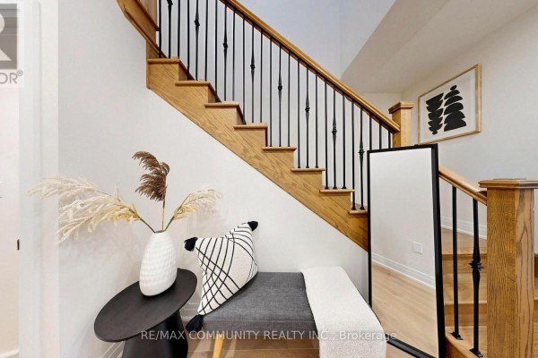 Foyer with a dark grey bench, decorative items, and a wooden staircase with black spindles. - 1034 Skyridge Boulevard, Pickering