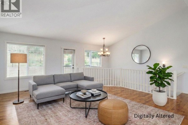 Living room with a dark leather sofa, light grey sectional, and light wood floors. - 10349 Copper Hill Lane, Lake Country