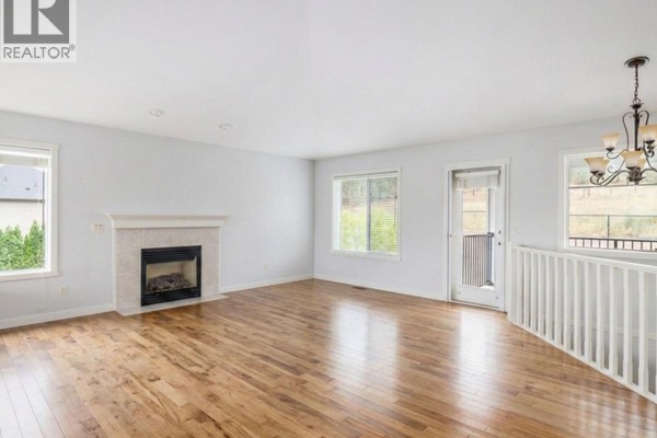 Living room with a light grey sectional sofa, coffee table, and round wall mirror. - 10349 Copper Hill Lane, Lake Country