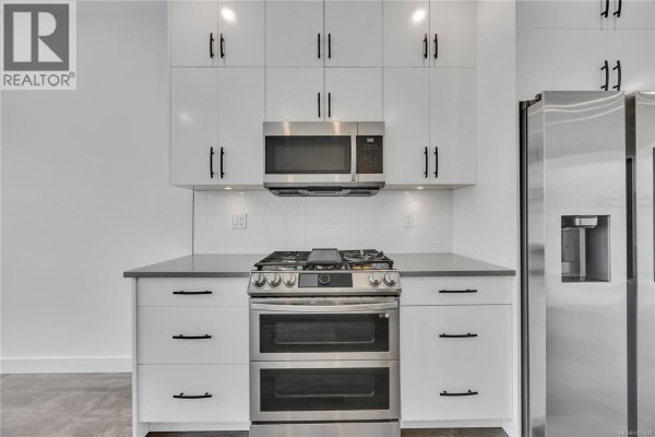 Close-up of a stainless steel gas range and double oven in a white kitchen. - 1036 Boxcar Close, Langford