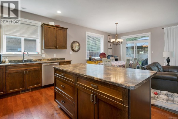 Bright dining area adjacent to the kitchen with a view of the backyard and a chandelier. - 1037 Cordero Cres, Campbell River