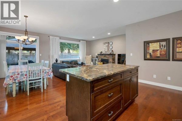 Open living and dining space with hardwood floors and large windows for natural light. - 1037 Cordero Cres, Campbell River