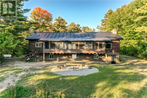 Log cabin with a screened porch and a stone fire pit in the yard. - 103a Northshore Road, Whitefish