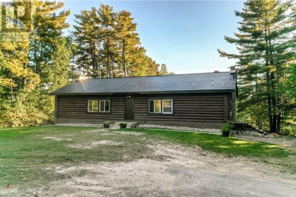 Exterior of a log cabin with a metal roof and white-trimmed windows. - 103a Northshore Road, Whitefish