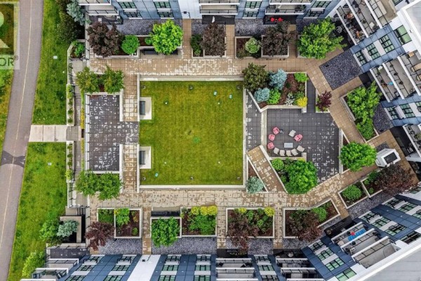 Aerial view of an apartment complex courtyard with green space and seating. - 104, 383 Smith Street Nw, Calgary