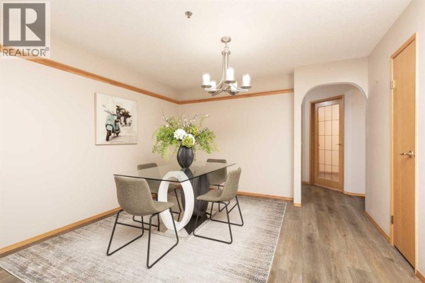 Open-concept kitchen and dining area with light wood cabinets, stainless steel appliances, and pendant lighting. - 104, 75 1 Avenue S, Lethbridge