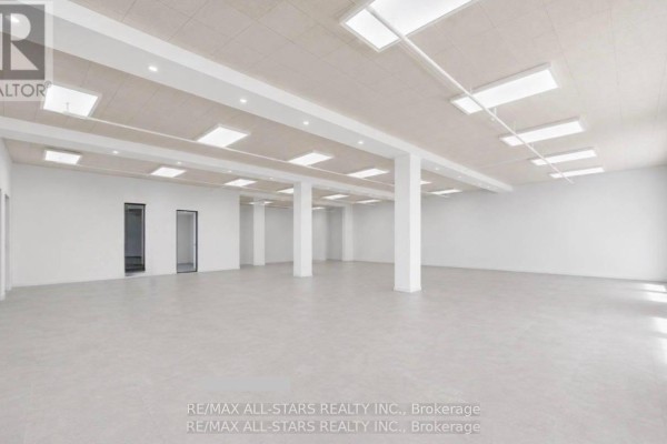 Wide view of an empty commercial space with plywood flooring and white columns. - 104 - 14 Mccaul Street, Toronto
