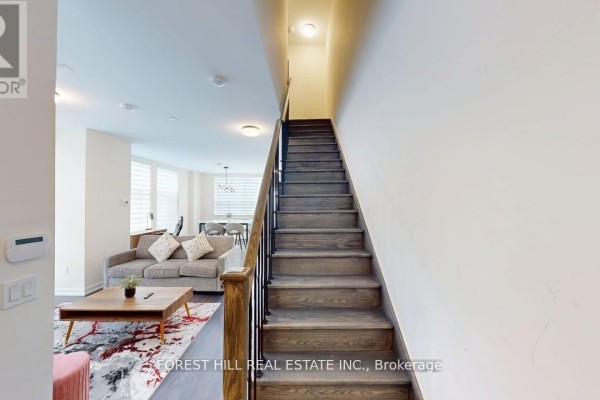 Wooden staircase with black metal railing leading to the second floor of the townhouse. - 104 - 16 Symes Road, Toronto