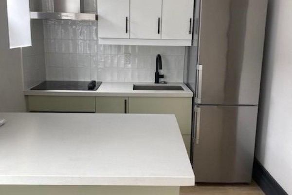 Kitchen with light green cabinets, white subway tile backsplash, and stainless steel refrigerator. - 104 - 204 Kingston Road, Toronto