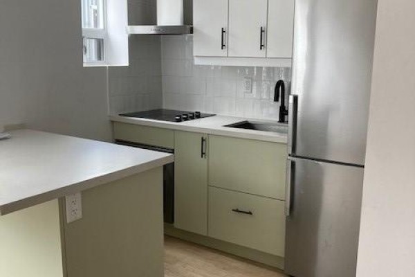 Kitchen with light green cabinets, white subway tile backsplash, and stainless steel refrigerator. - 104 - 204 Kingston Road, Toronto