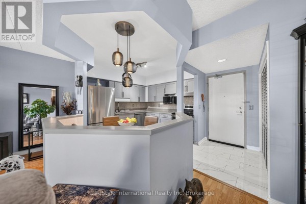 Open concept living and dining area overlooking a light grey kitchen and entrance. - 104 - 208 Silvercreek Parkway N, Guelph