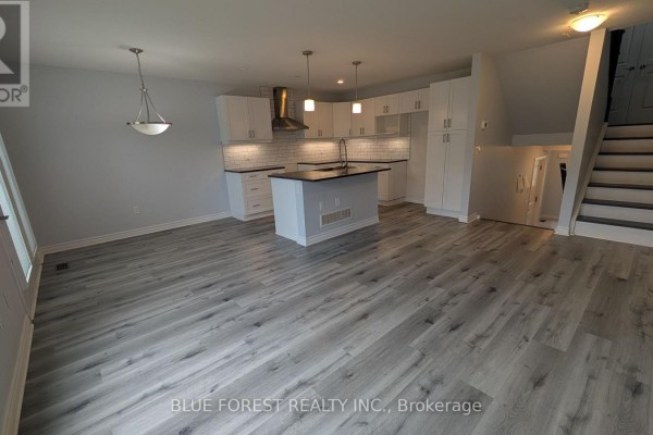 Open-concept living space with dining area, island kitchen, and a back deck view. - 104 - 3400 Castle Rock Place, London South