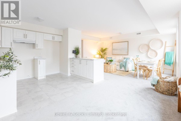 Open concept living space showing a white kitchen and a living room with a sofa and painting. - 104 - 48 Maple Avenue, Asphodel Norwood