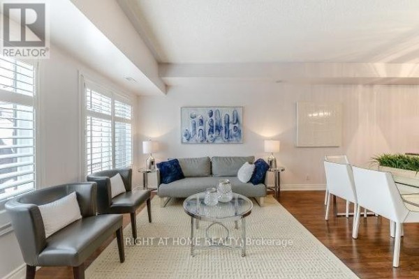 Living room with grey sofa, chairs, glass coffee table, and hardwood floors. - 104 - 5 Richgrove Drive E, Toronto