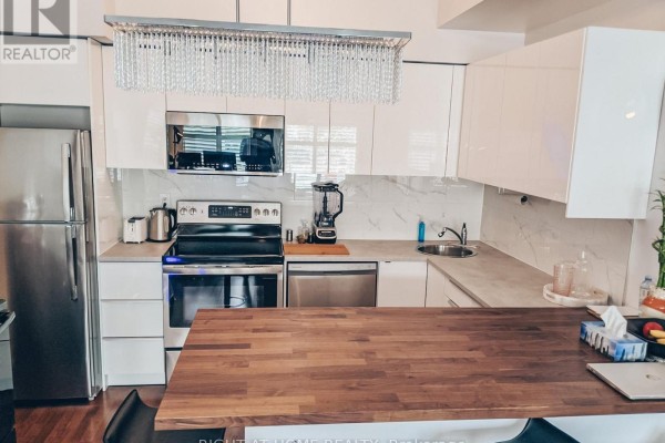 Modern kitchen with stainless steel appliances, white cabinetry, and a large wood island. - 104 - 5 Richgrove Drive E, Toronto