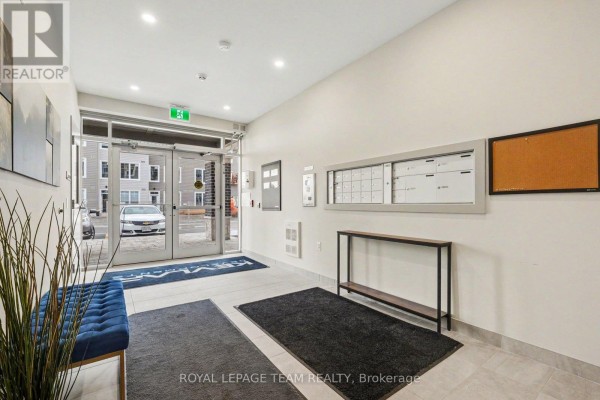 Building entrance lobby with blue bench, mailboxes, and tiled flooring. - 104 - 5874 County Rd #19 Road, North Grenville