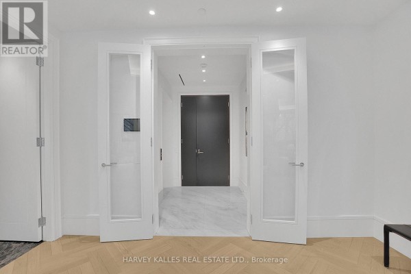 Double doors with frosted glass panels open to a marble-tiled hallway with a dark door. - 104 - 7 Dale Avenue, Toronto