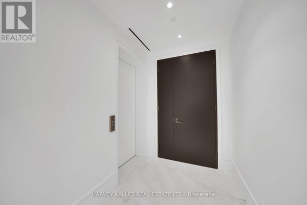 Interior hallway with white walls, marble floor, and a dark double door and elevator. - 104 - 7 Dale Avenue, Toronto