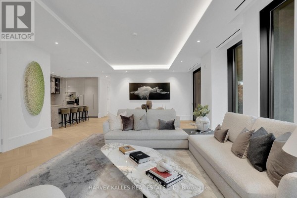 Living area with sectional sofa, marble coffee table, and view of kitchen with island seating. - 104 - 7 Dale Avenue, Toronto
